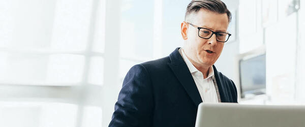 Mitarbeiter im technischen B2B Vertrieb steht am Laptop und arbeitet hybrid WACHSTUMSPLAN berät